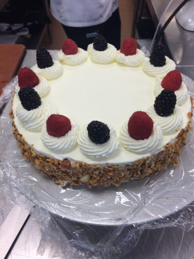 I cake decorated with whipped cream, almond slivers and berries